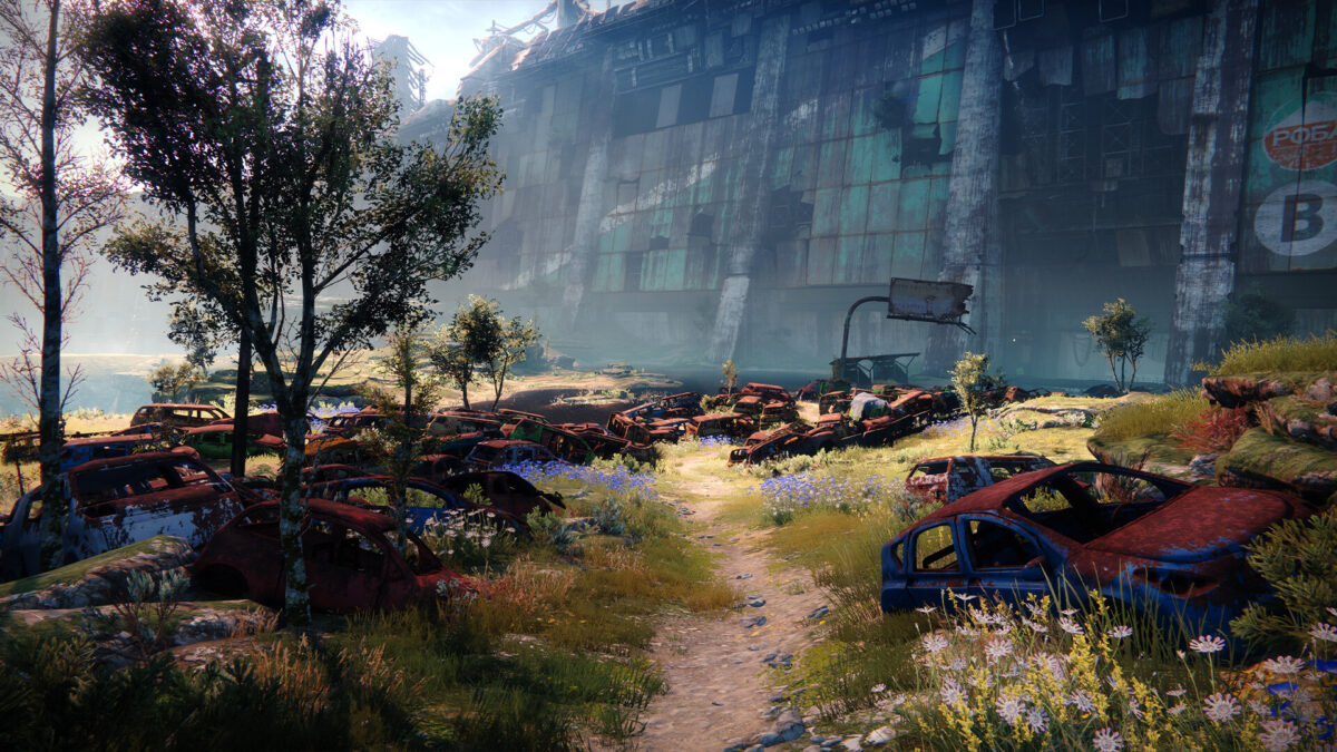 Destiny 2 screenshot of a road through the European Dead Zone with wrecked cars and a wall at sunset