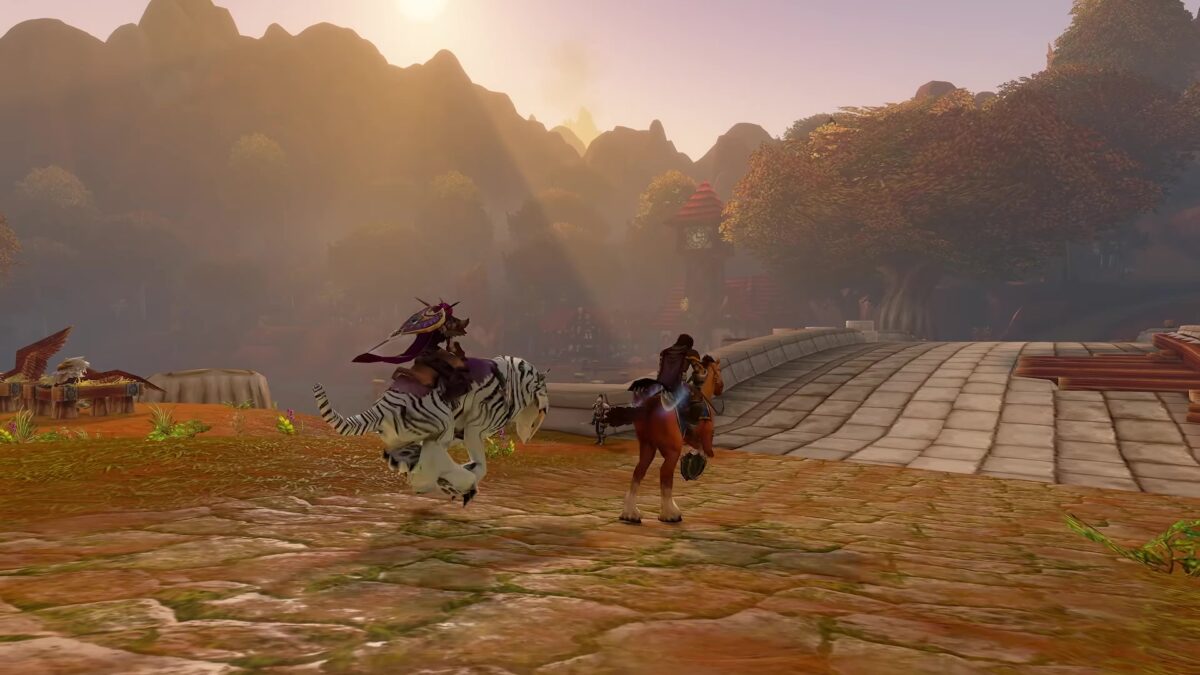Two mounted World of Warcraft: Forever characters riding across a stone bridge at sunset in the gameplay trailer
